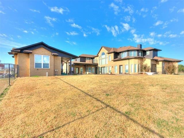 rear view of house with brick siding, a lawn, and fence