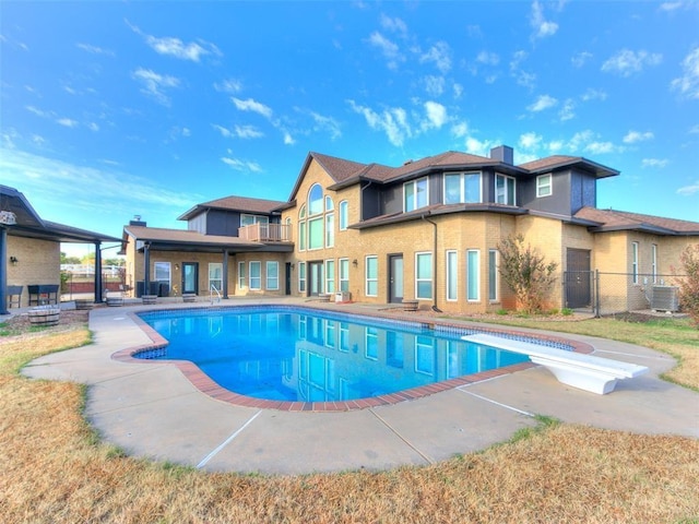 view of swimming pool with a diving board, central AC, fence, and a fenced in pool