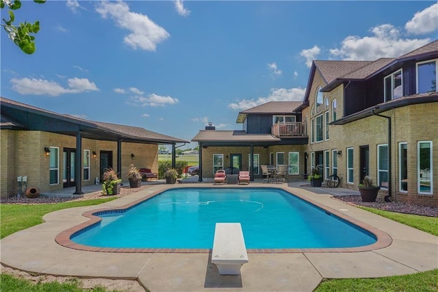 pool with a diving board and a patio area