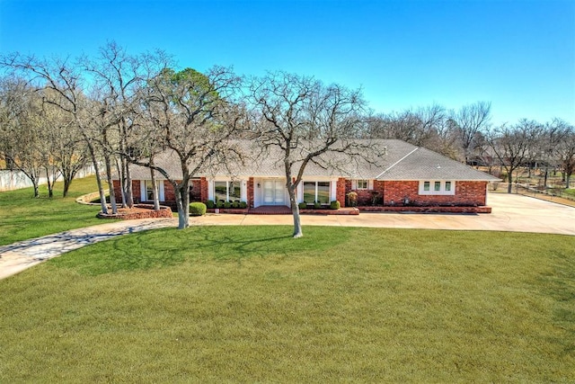 view of front of home with brick siding, curved driveway, and a front yard