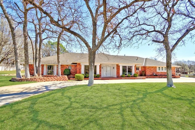 ranch-style home featuring brick siding, curved driveway, and a front yard