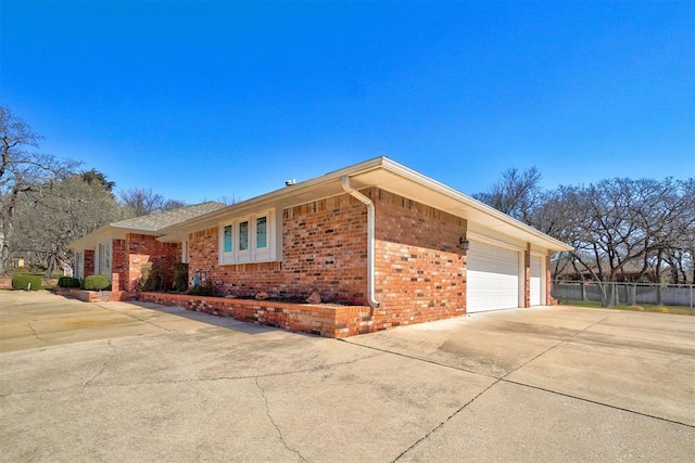 view of front facade featuring a garage, brick siding, driveway, and fence