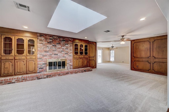 unfurnished living room featuring visible vents, light colored carpet, a fireplace, and ceiling fan