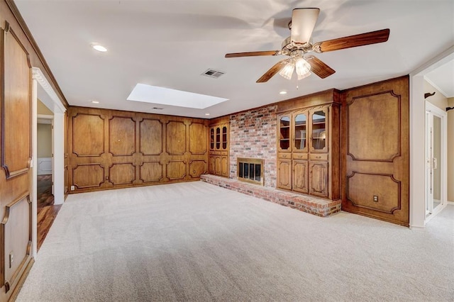 unfurnished living room featuring visible vents, light colored carpet, a skylight, and a ceiling fan