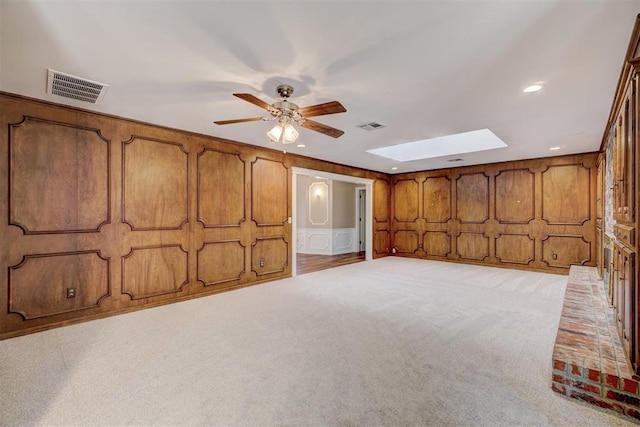 interior space with visible vents, light colored carpet, a skylight, and a ceiling fan