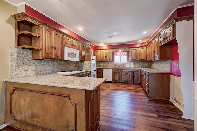 kitchen featuring visible vents, dark wood-type flooring, white appliances, a peninsula, and brown cabinetry