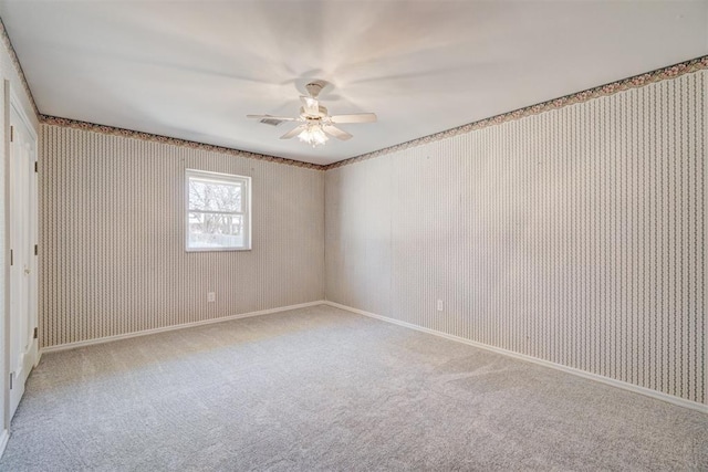 carpeted empty room with wallpapered walls, a ceiling fan, visible vents, and baseboards