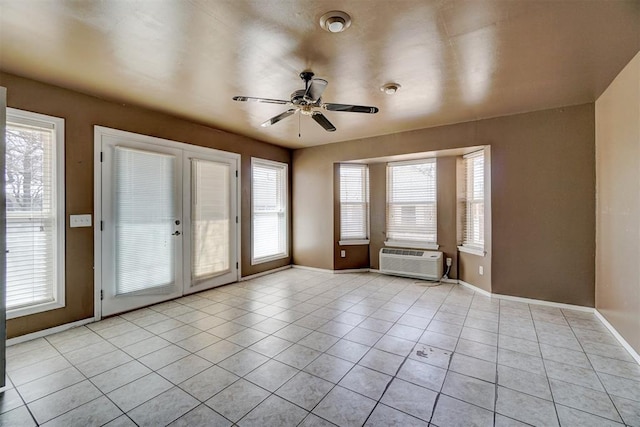 unfurnished room with baseboards, light tile patterned flooring, a ceiling fan, and a wall unit AC