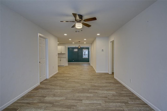 empty room with ceiling fan, light wood-type flooring, baseboards, and recessed lighting