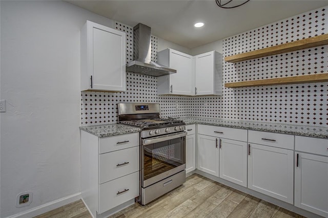 kitchen with wall chimney exhaust hood, stainless steel gas range, light wood-type flooring, open shelves, and backsplash