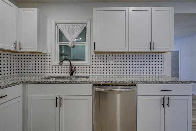 kitchen with tasteful backsplash, white cabinets, a sink, light stone countertops, and dishwasher