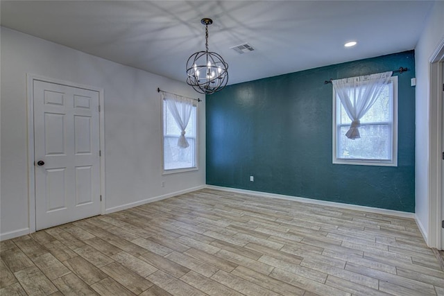 unfurnished room featuring an inviting chandelier, baseboards, visible vents, and wood finished floors