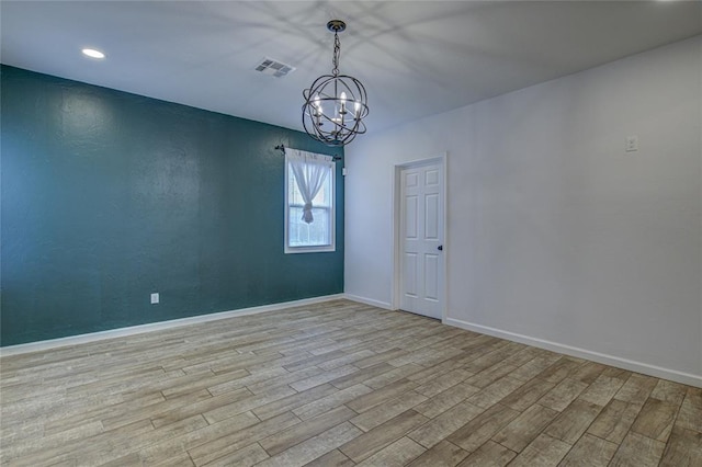 empty room with an inviting chandelier, baseboards, visible vents, and wood finished floors