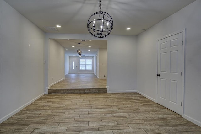 empty room with baseboards, ceiling fan with notable chandelier, wood finished floors, and recessed lighting