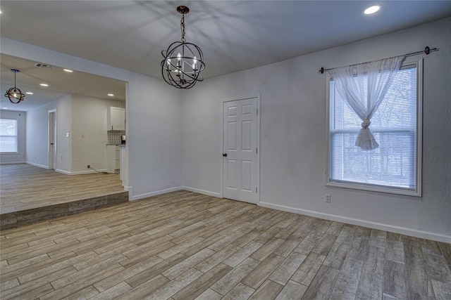 empty room with light wood-style flooring, baseboards, a notable chandelier, and recessed lighting