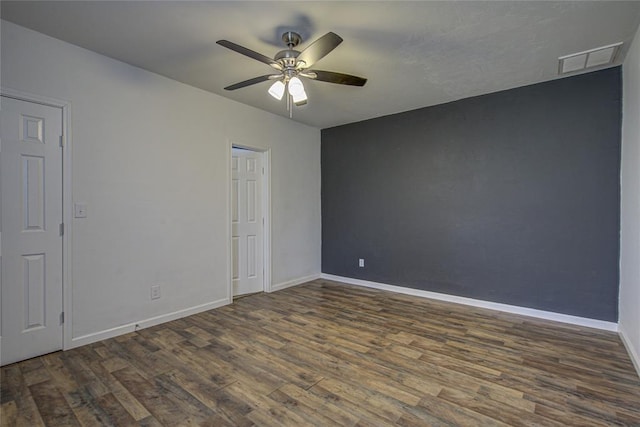 unfurnished room with a ceiling fan, wood finished floors, visible vents, and baseboards