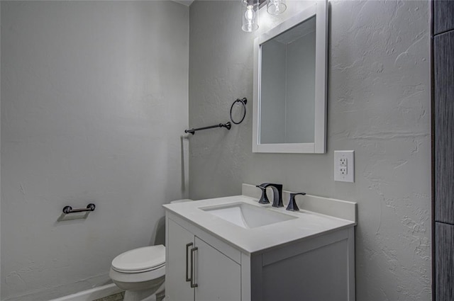 half bath with a textured wall and vanity