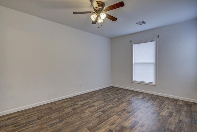 spare room featuring baseboards, visible vents, ceiling fan, and dark wood-style flooring