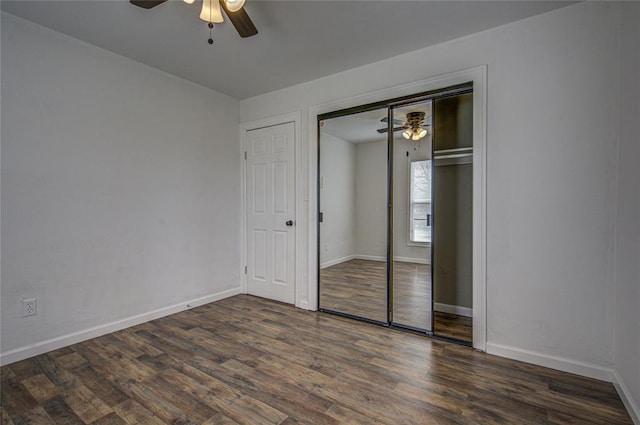 unfurnished bedroom featuring a closet, dark wood-style flooring, baseboards, and a ceiling fan