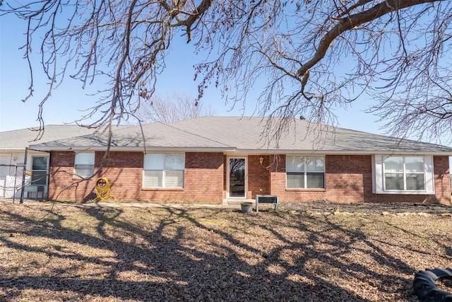 view of front of home with brick siding, a shingled roof, and a front yard