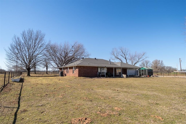 back of house featuring brick siding, fence, and a lawn