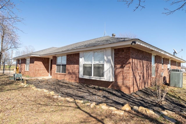 view of home's exterior with fence, cooling unit, and brick siding