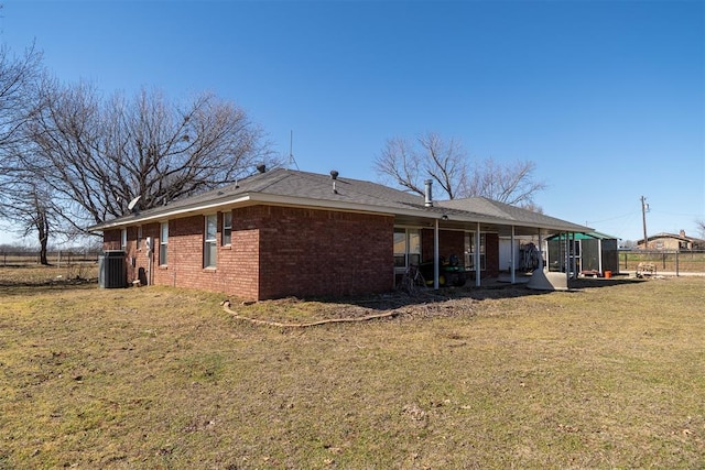 back of house featuring brick siding, a lawn, fence, and central air condition unit