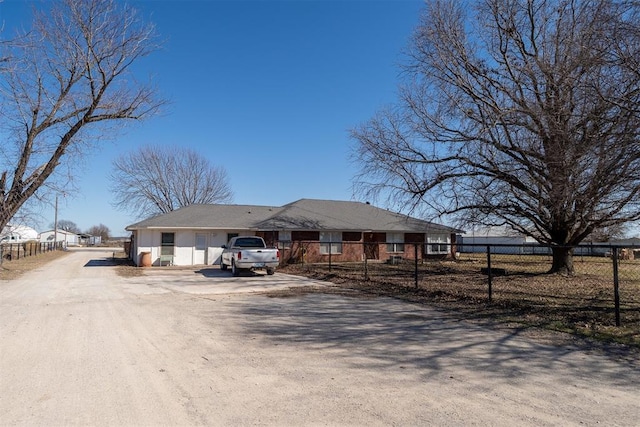 single story home with a fenced front yard and dirt driveway