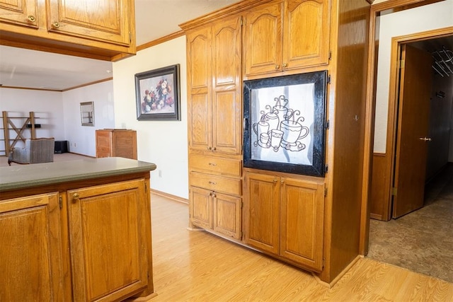 kitchen with brown cabinetry, crown molding, and light wood finished floors