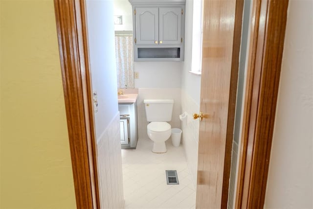 bathroom with tile walls, visible vents, toilet, vanity, and tile patterned flooring