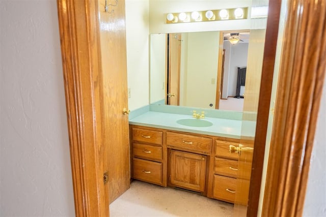 bathroom with a textured wall, a ceiling fan, and vanity