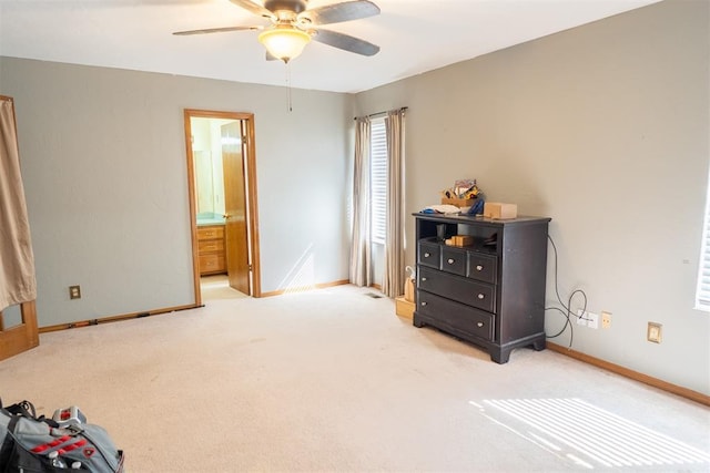 bedroom featuring light colored carpet, ceiling fan, baseboards, and ensuite bathroom