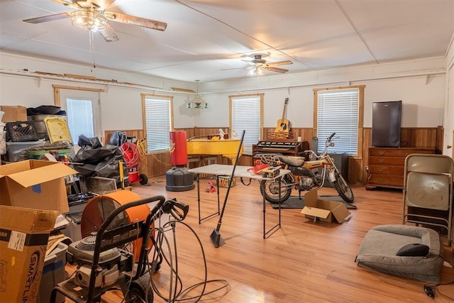 interior space featuring wainscoting, ceiling fan, wood walls, and light wood finished floors