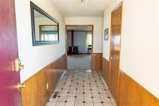 hall with light floors, wainscoting, and wooden walls