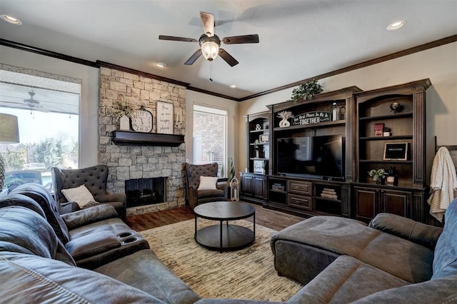 living area featuring a stone fireplace, wood finished floors, and a ceiling fan