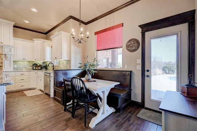 kitchen featuring dark wood-style flooring, white cabinets, stainless steel dishwasher, a wealth of natural light, and decorative backsplash