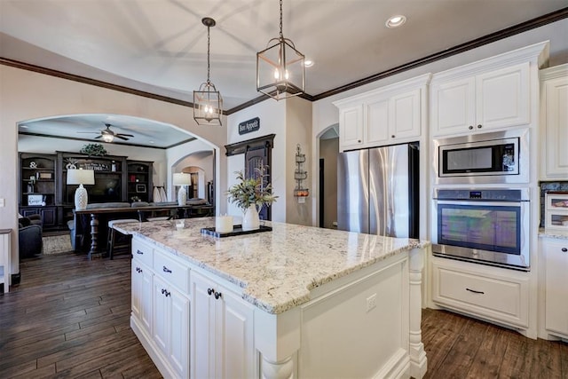 kitchen featuring white cabinetry, a kitchen island, arched walkways, and stainless steel appliances