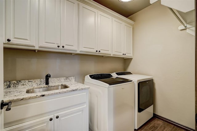 laundry room with cabinet space, baseboards, dark wood-type flooring, independent washer and dryer, and a sink