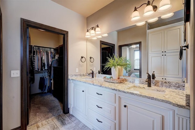 bathroom with a walk in closet, a sink, and double vanity