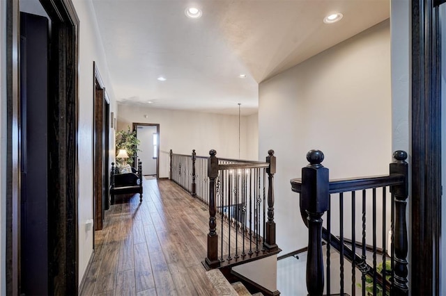 corridor with hardwood / wood-style flooring, an upstairs landing, and recessed lighting