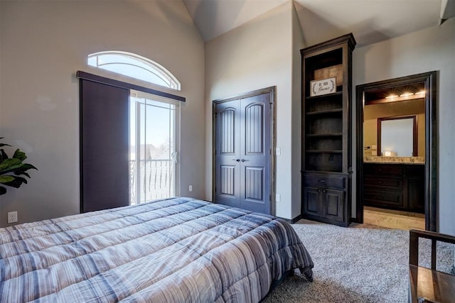 carpeted bedroom featuring lofted ceiling, a closet, and ensuite bath