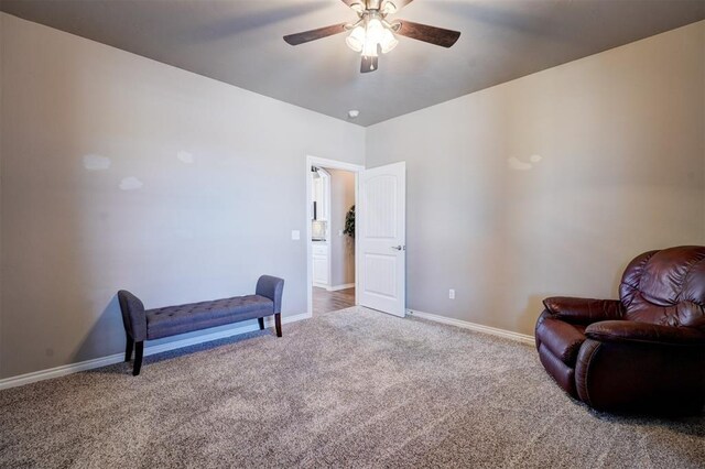 sitting room with carpet floors, a ceiling fan, and baseboards