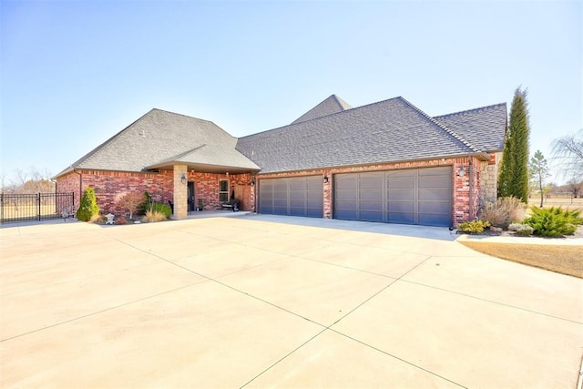 french country home with driveway, a shingled roof, an attached garage, fence, and brick siding