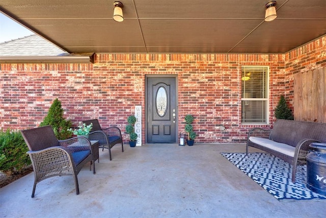 property entrance with brick siding, a patio, and an outdoor living space