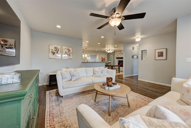 living room featuring baseboards, a stone fireplace, dark wood-type flooring, and recessed lighting