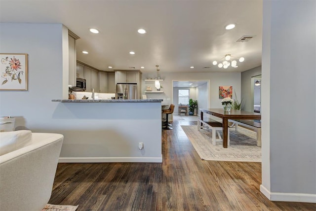 kitchen featuring dark wood finished floors, recessed lighting, appliances with stainless steel finishes, stone countertops, and a peninsula