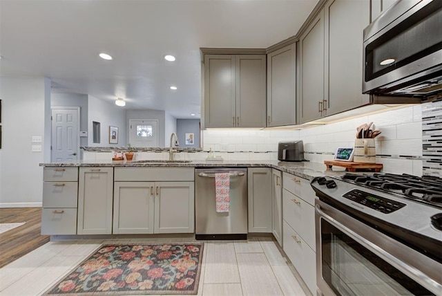 kitchen with a peninsula, decorative backsplash, stainless steel appliances, and a sink