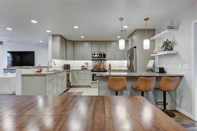 kitchen featuring decorative backsplash, appliances with stainless steel finishes, a peninsula, open shelves, and a sink