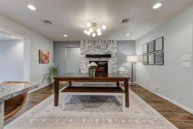 dining space with dark wood-type flooring, a brick fireplace, and visible vents