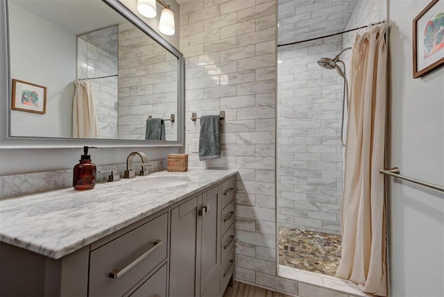 bathroom with a tile shower and vanity